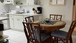 A kitchen with white cabinets, a dining table with chairs, a coffee maker, and a chandelier. - Magnificent Beach front condo with pool and restaurant/bar (Freeport)