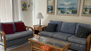 A living room with two sofas, a glass coffee table, and a patterned rug. - Magnificent Beach front condo with pool and restaurant/bar (Freeport)