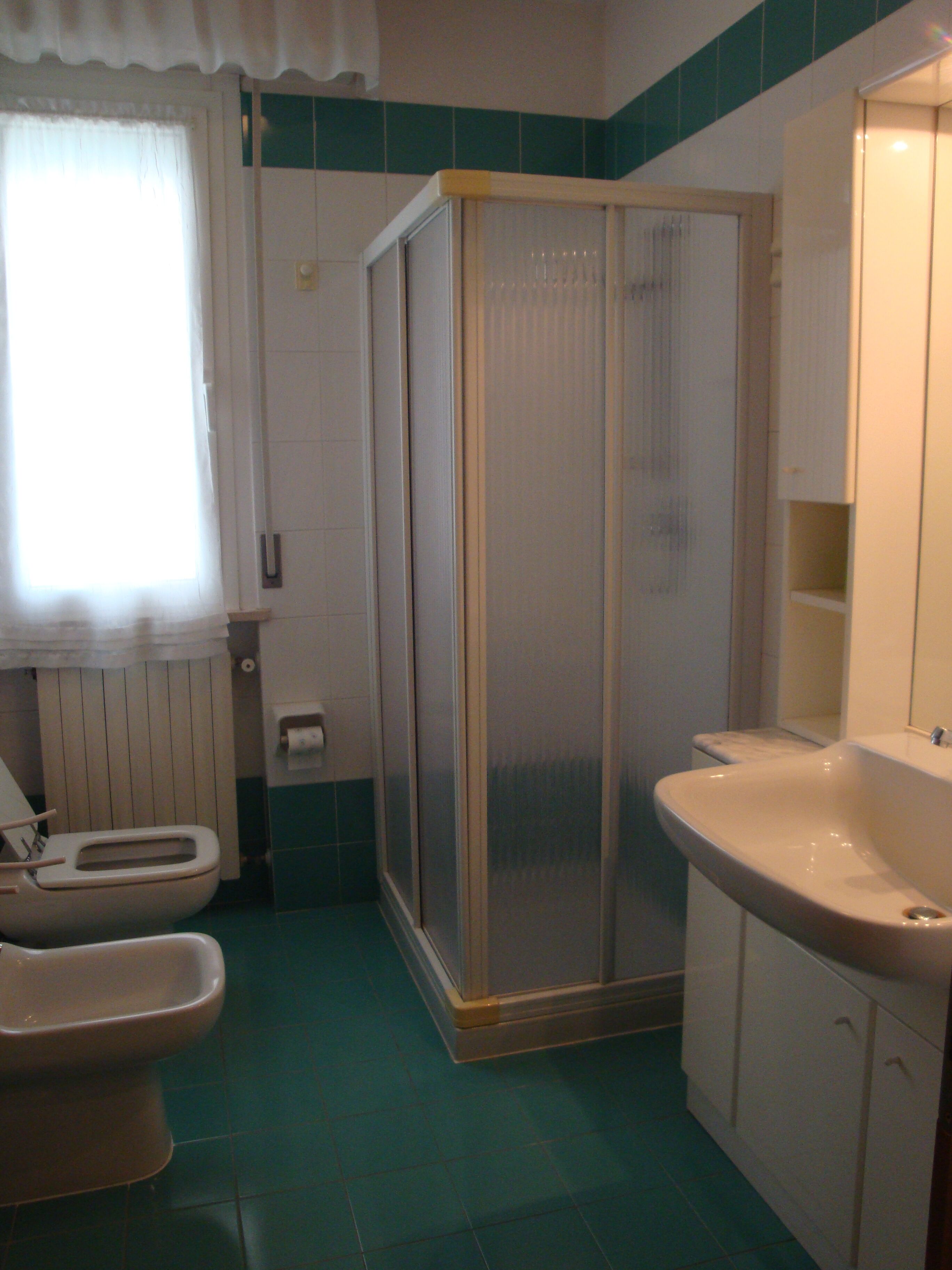 Un bagno con toilette, bidet, cabina doccia e lavandino.