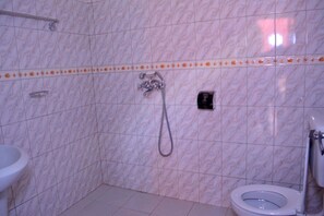 A bathroom with a marble wall, a shower, a toilet, and a sink. - Sadrina Comfort Cottages (Kampala)