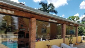 A poolside area with a brick fireplace, lounge chairs, and a small table. - Beautiful house with the best View (Sao Roque)