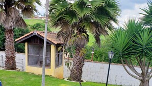 A small yellow building with a tiled roof, surrounded by lush greenery and palm trees. - Beautiful house with the best View (Sao Roque)
