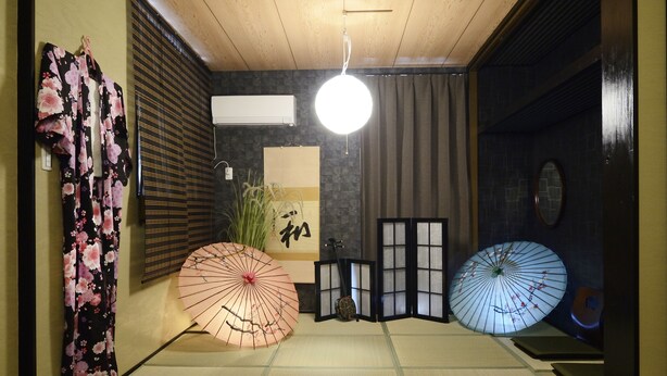 A traditional Japanese room with tatami flooring, a shoji screen, and two kakebutō umbrellas. - South Island (Itoman)