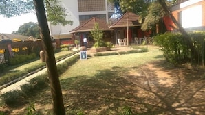 Un patio con un camino empedrado, un pequeño jardín y un edificio con tejado de baldosas.