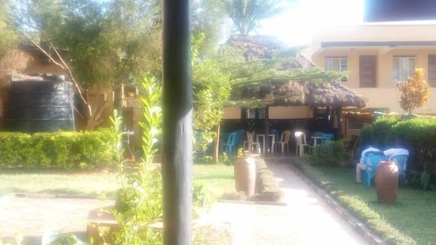 Un jardín con una construcción de paja, mobiliario exterior y un depósito de agua grande.