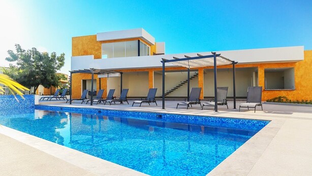 Un hôtel moderne doté d’une piscine, de chaises longues et d’un patio couvert.