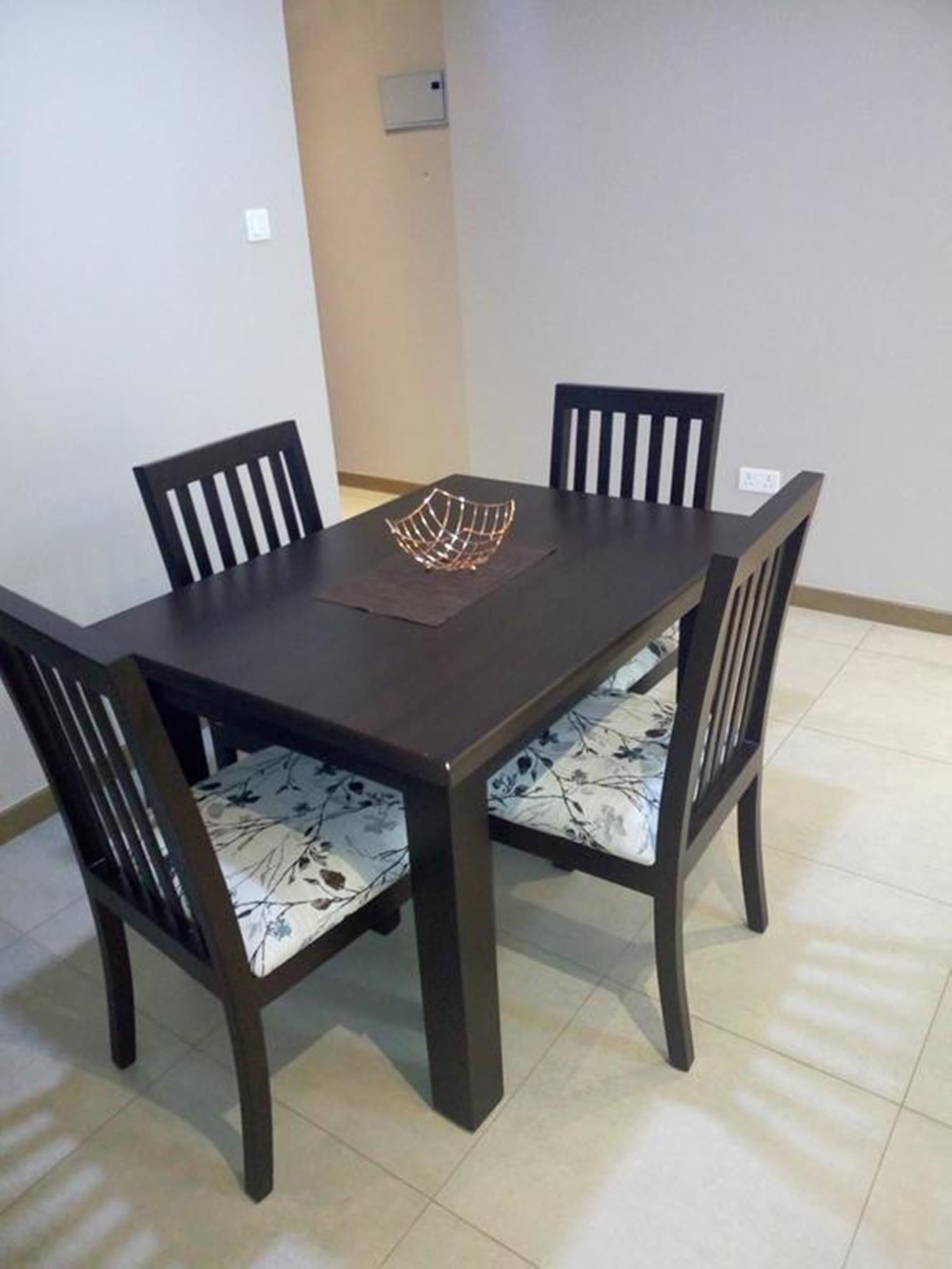 A dining table with four chairs, each with a floral cushion.