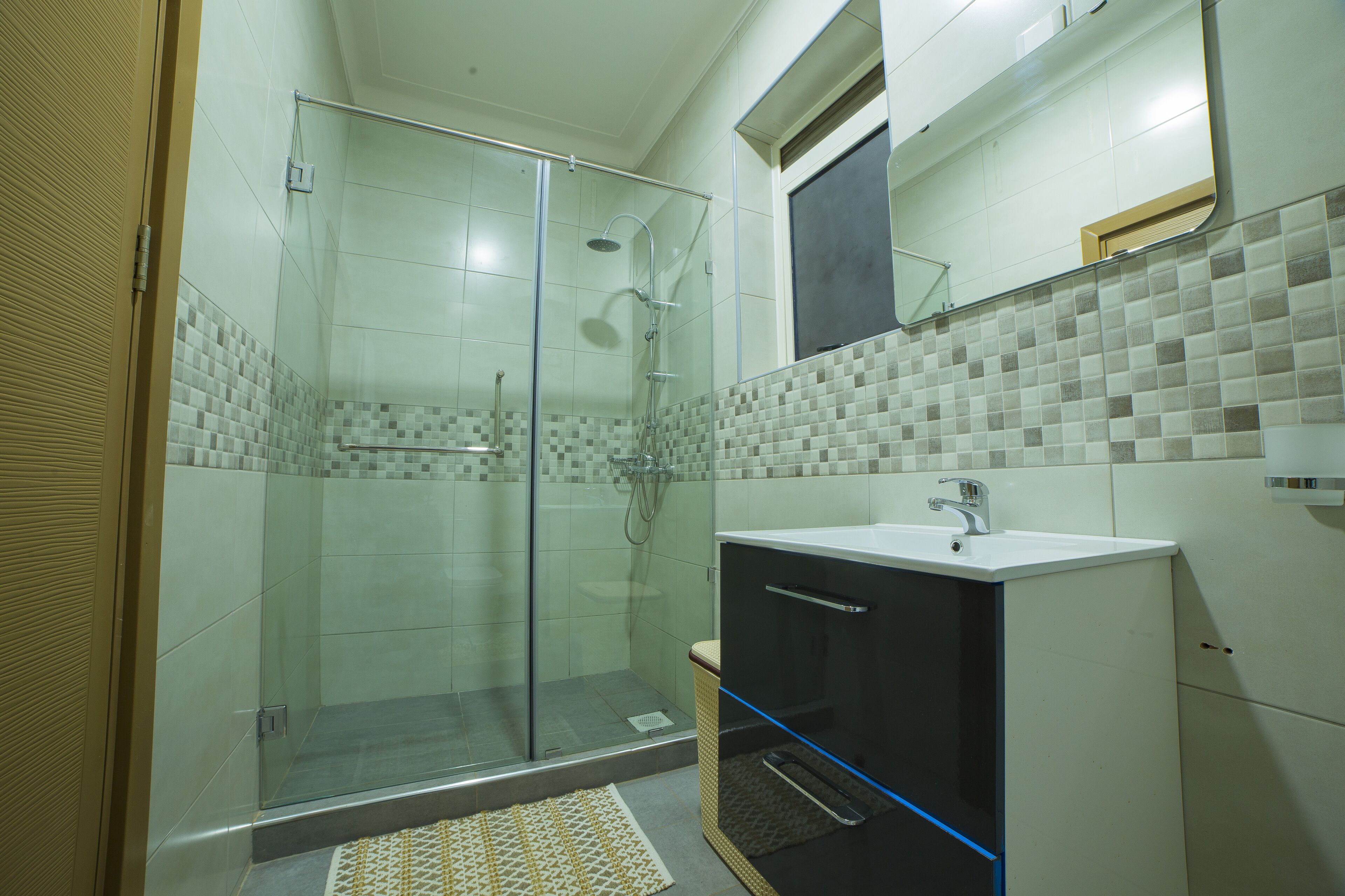 A bathroom with a glass-enclosed shower, a white sink, and a tiled backsplash.