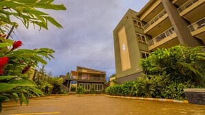 A modern building with a sign reading "Ruby's Restaurant" and a parking area with a paved walkway. - Natra Apartments (Kampala)