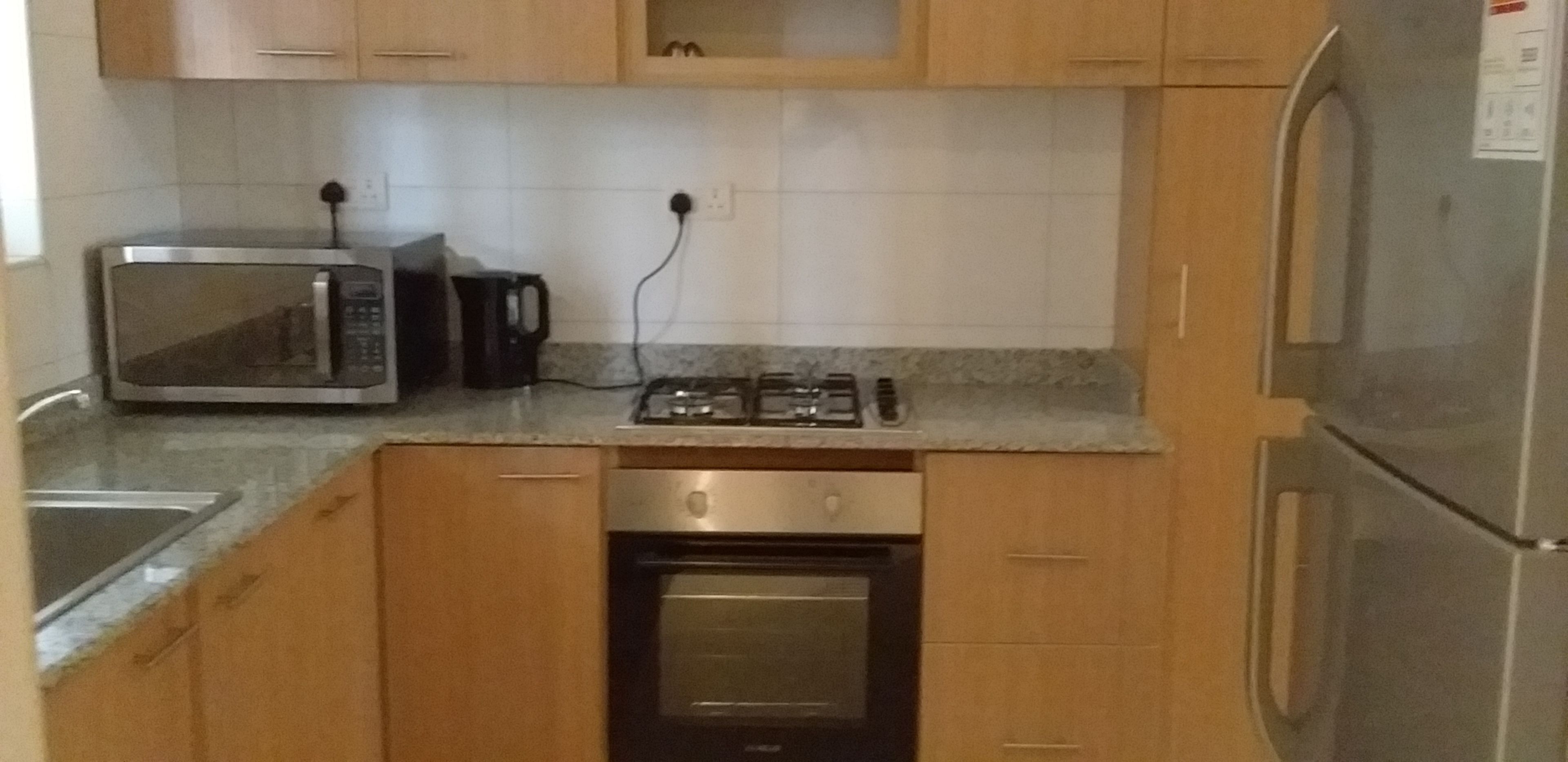 A compact kitchen with a microwave, coffee maker, stove, oven, and refrigerator.