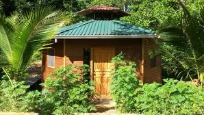 A small wooden structure with a green roof, surrounded by lush greenery and plants. - River View Cabin and Hot Springs (Arizona)