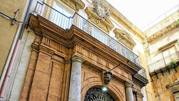 A historic building with a large arched entrance, columns, and a balcony with railings. - Natoli Apartments - Gigi House (Palermo, Italia)