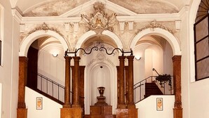 A grand staircase with ornate columns, a central fountain, and a decorative ceiling. - Natoli Apartments - Gigi House (Palermo, Italia)