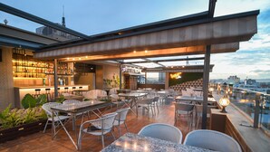 Un bar situé sur le toit, avec une terrasse, un espace bar et une vue sur les toits de la ville.