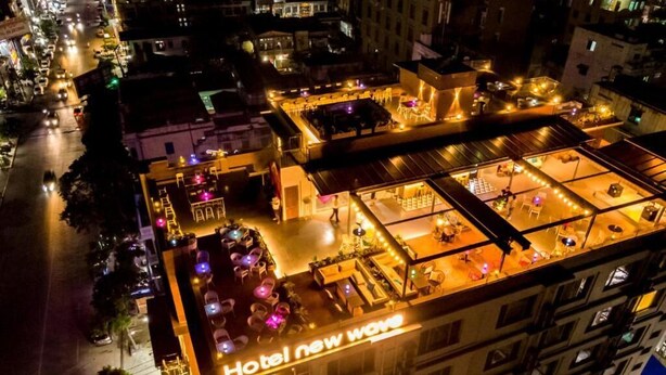 Un hôtel doté d’une terrasse sur le toit, avec des sièges en plein air, et d’une enseigne indiquant « Hôtel New Wave ».
