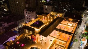 Un bar situé sur un toit, avec une terrasse et un espace piscine, le tout entouré d’immeubles.