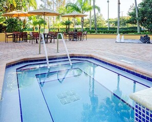 Relax by the pool surrounded by lush greenery and shaded seating areas.