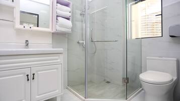 A modern bathroom with a glass-enclosed shower, white fixtures, and a toilet.