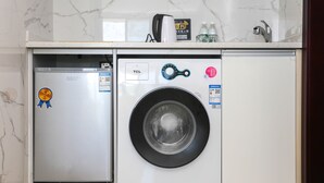 A compact washing machine and dishwasher unit in a kitchen with marble countertops and a tiled backsplash. - Seacliff Apartment (Shantou)