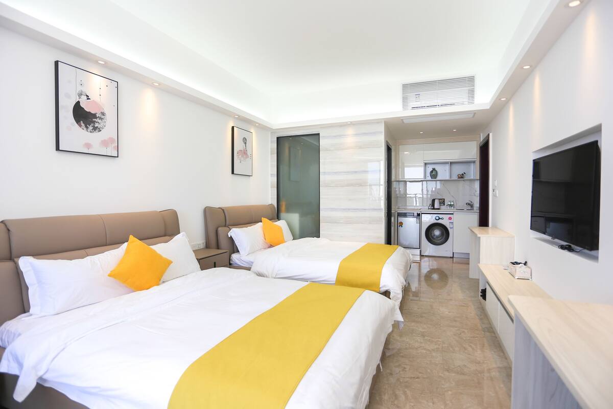 A hotel room with two beds, a washing machine, and a TV.