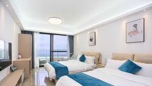 A modern hotel room with two beds, a desk, and a large window offering a view of the sea. - Seacliff Apartment (Shantou)