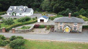 A white house with a grey roof, a stone building with a yellow door, and a small white shed.