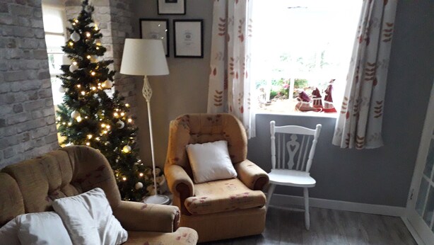 A living room with a sofa, armchair, and a Christmas tree. - Cloverhill  Gate Lodge       Relax Refresh and Unwind  promises tranquillity (Co Cavan)