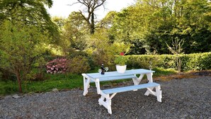 A white picnic table with benches in a garden setting.