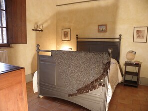 Relax in a cozy space with a metal-framed bed, patterned throw blanket, and a bedside table with a lamp and clock.