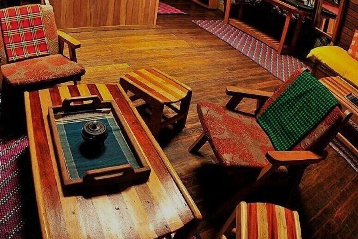 Um quarto aconchegante com piso de madeira, mesa de bilhar e várias cadeiras listradas.