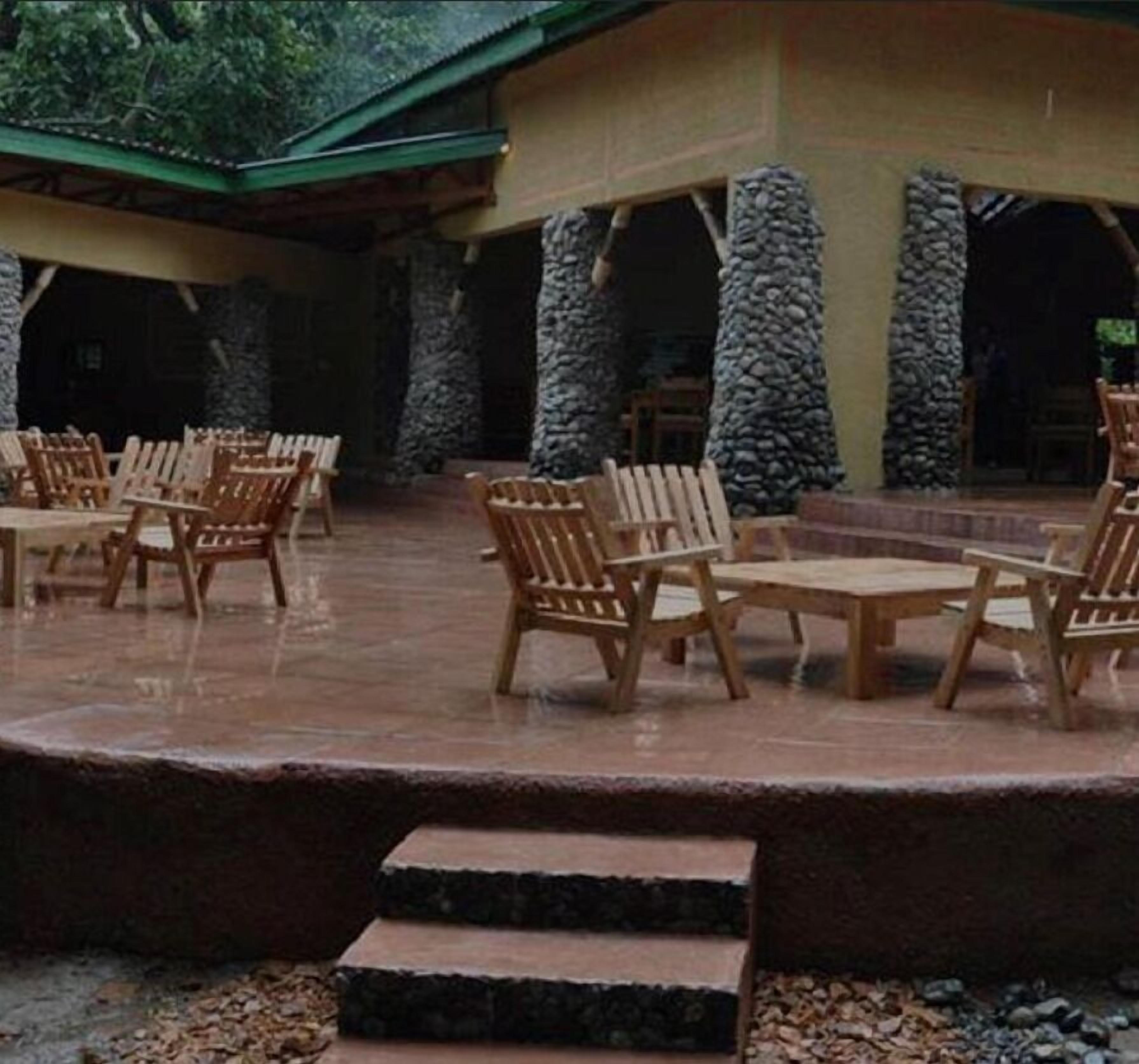 An outdoor patio area with wooden furniture and stone pillars.