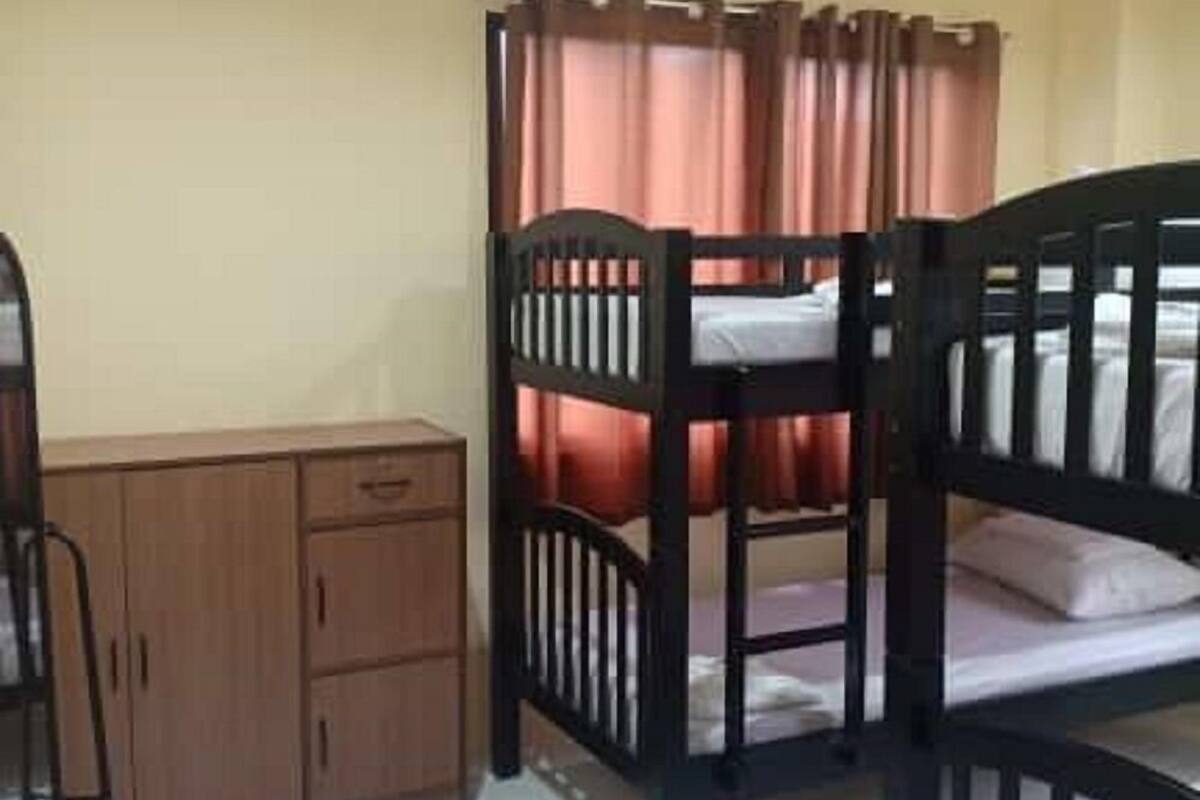 A room with bunk beds, a wooden cabinet, and a ceiling fan.