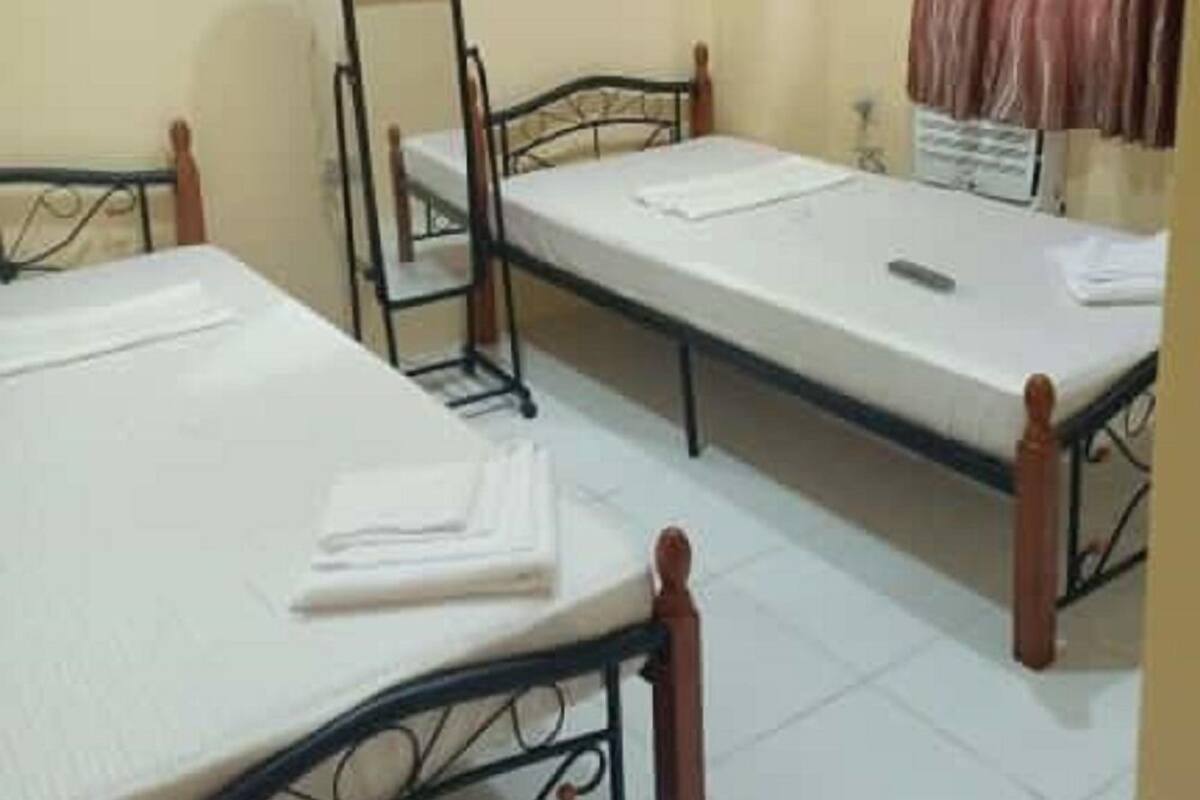 A dormitory room with two single beds, a mirror, a telephone, and a curtain.