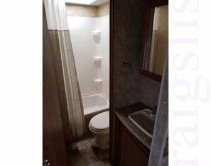 Bathroom features a toilet, bathtub, and sink with a mirror above.