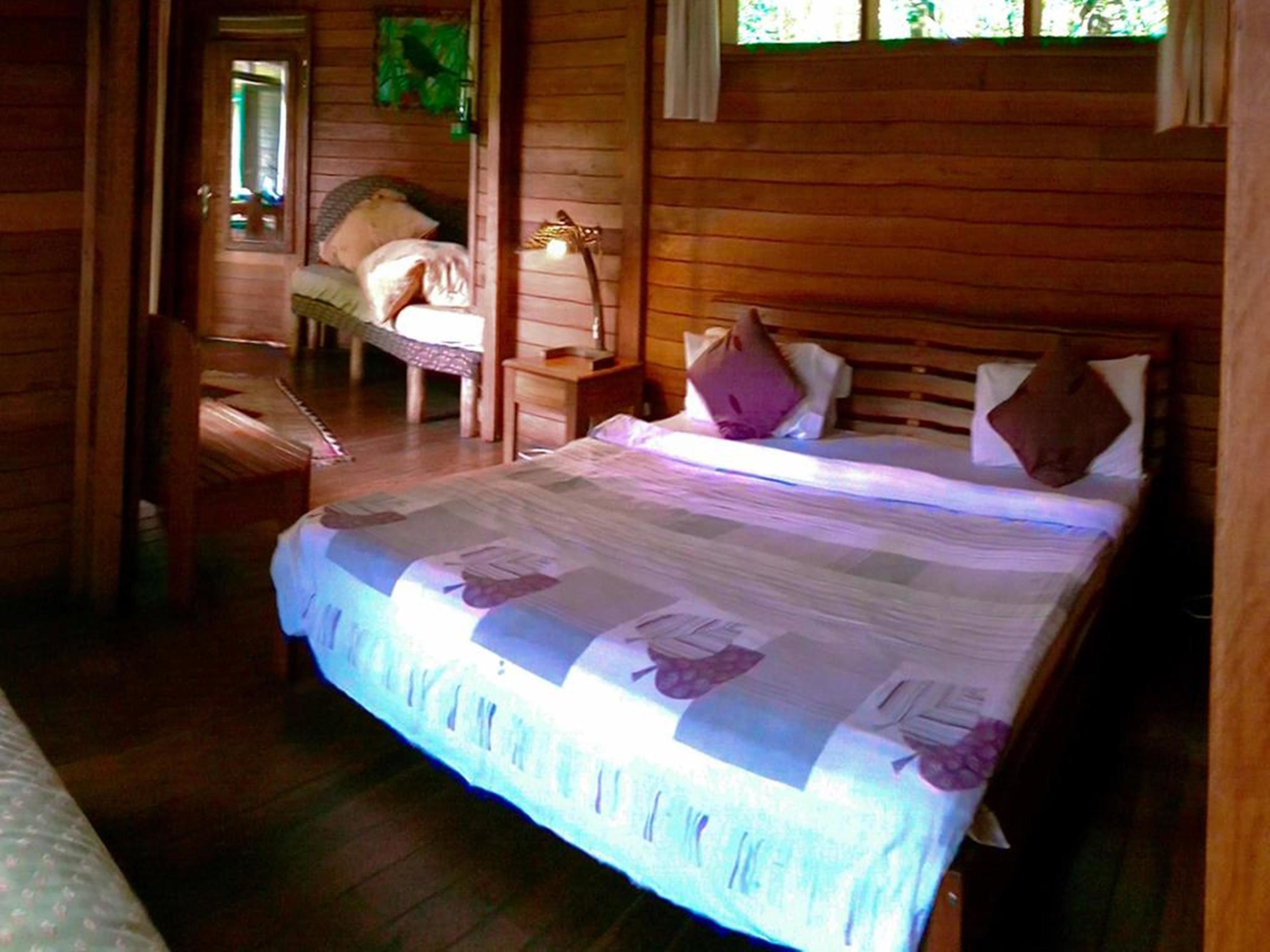 A wooden cabin bedroom with a bed, nightstands, and a window.