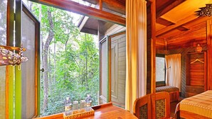 A wooden cabin with a dining area and a bed. - The Rainforest Geo Lodge (Lugazi)