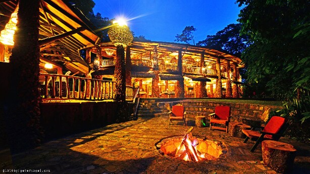 A rustic lodge with a fire pit and outdoor seating. - The Rainforest Geo Lodge (Lugazi)
