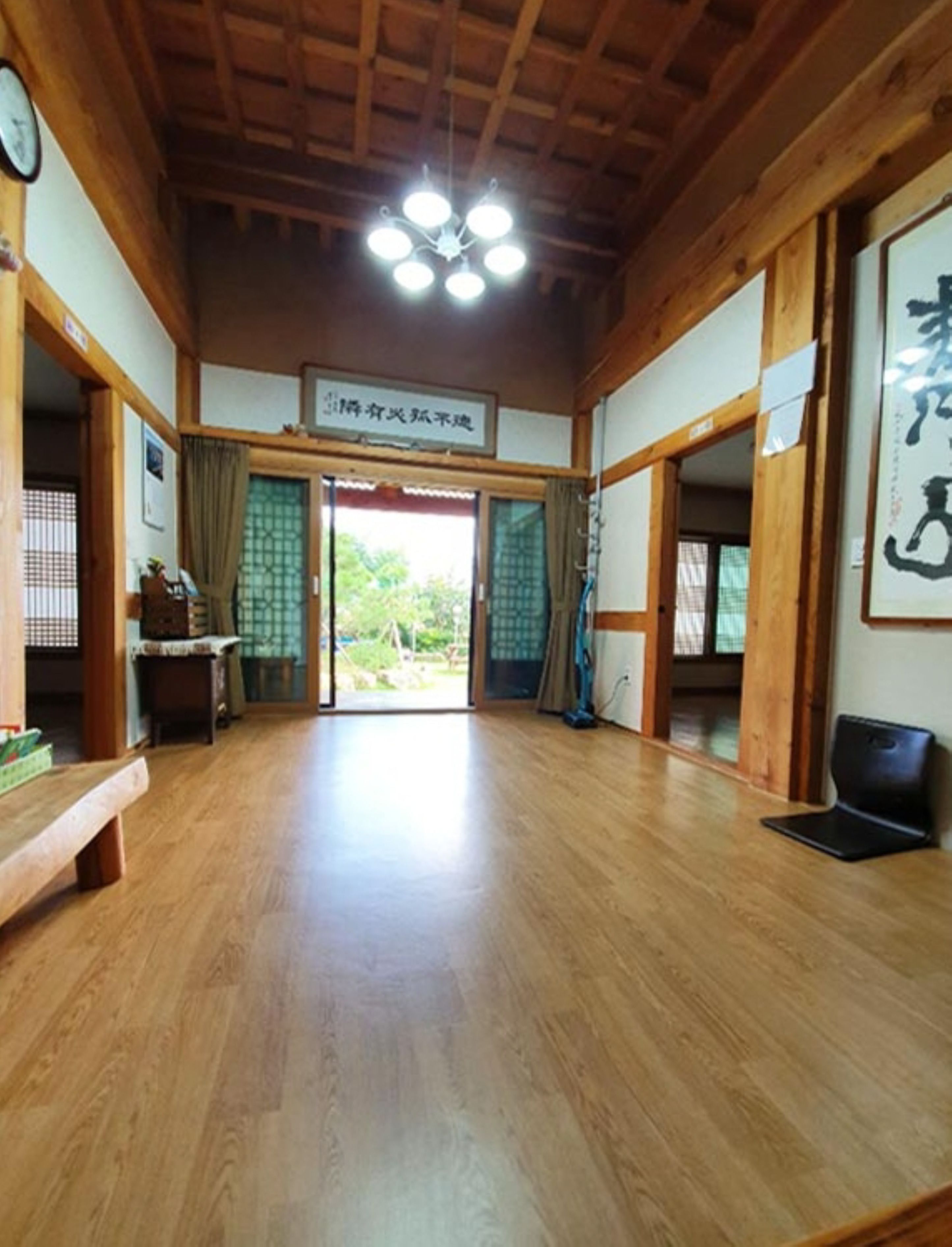 A traditional Japanese room with wooden floors, a ceiling fan, and sliding doors leading to an outdoor area.