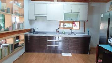 A compact kitchen with wooden beams, white cabinets, a central island, and a built-in bookshelf.
