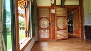 Un intérieur japonais traditionnel avec des portes coulissantes, un plancher en bois et une vue sur l’extérieur.