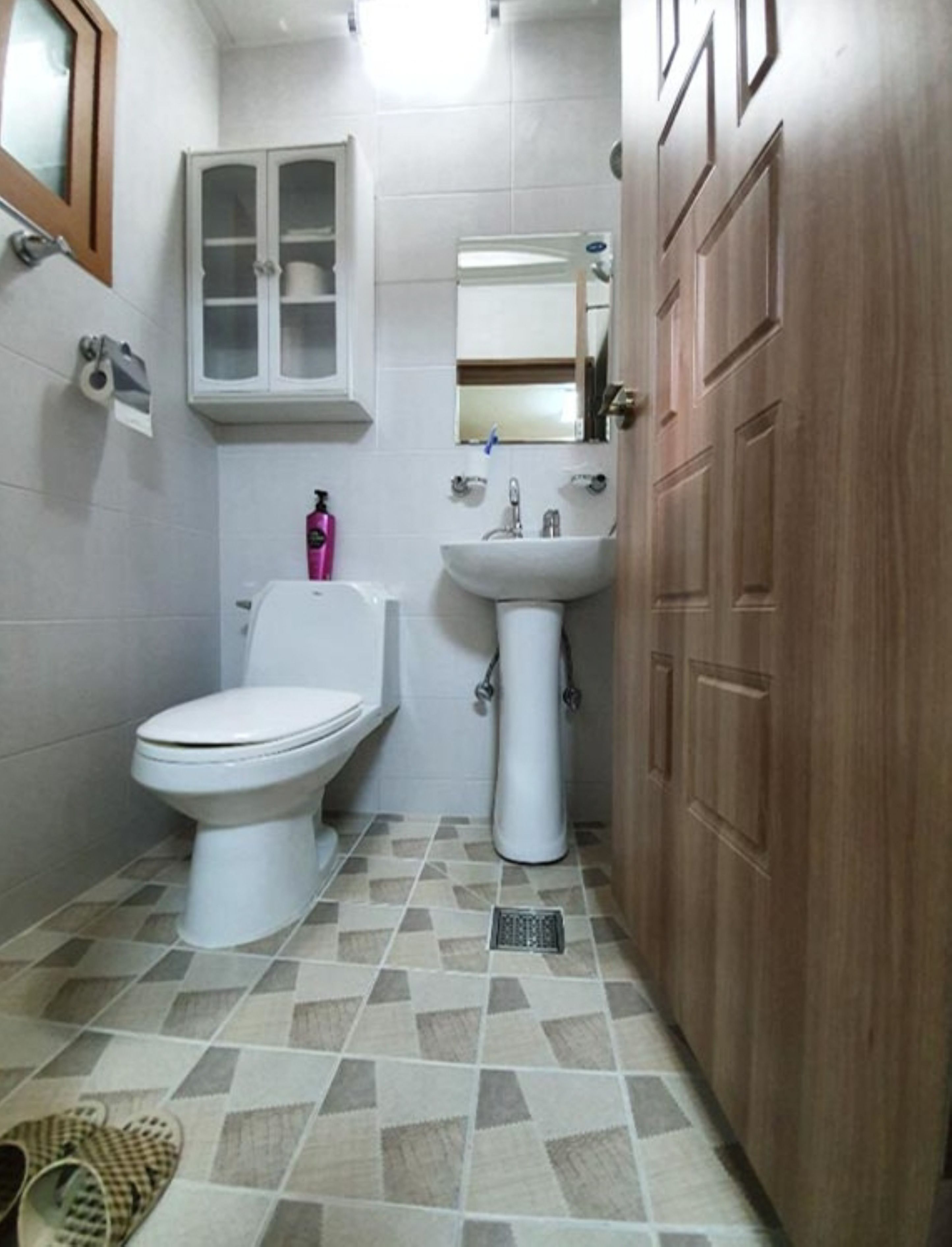 Uma casa de banho pequena com sanita, lavatório e armário.