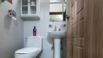 Uma casa de banho pequena com sanita, lavatório e armário.