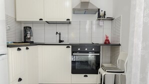 A compact kitchen with white cabinets, a black stove, and a coffee maker. - Mini Apartments in Brindisi center Corso Garibaldi (Brindisi)