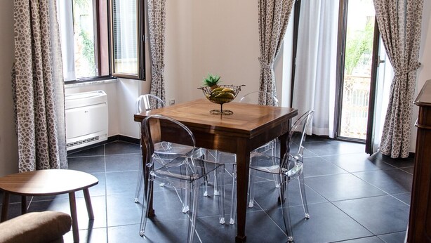 A dining area with a wooden table, clear chairs, and a small plant on the table. - Mini Apartments in Brindisi center Corso Garibaldi (Brindisi)