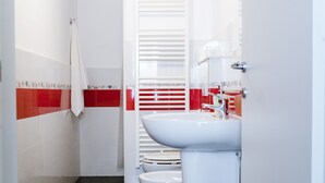 A bathroom with white and red tiled walls, a white sink, and a toilet. - Mini Apartments in Brindisi center Corso Garibaldi (Brindisi)