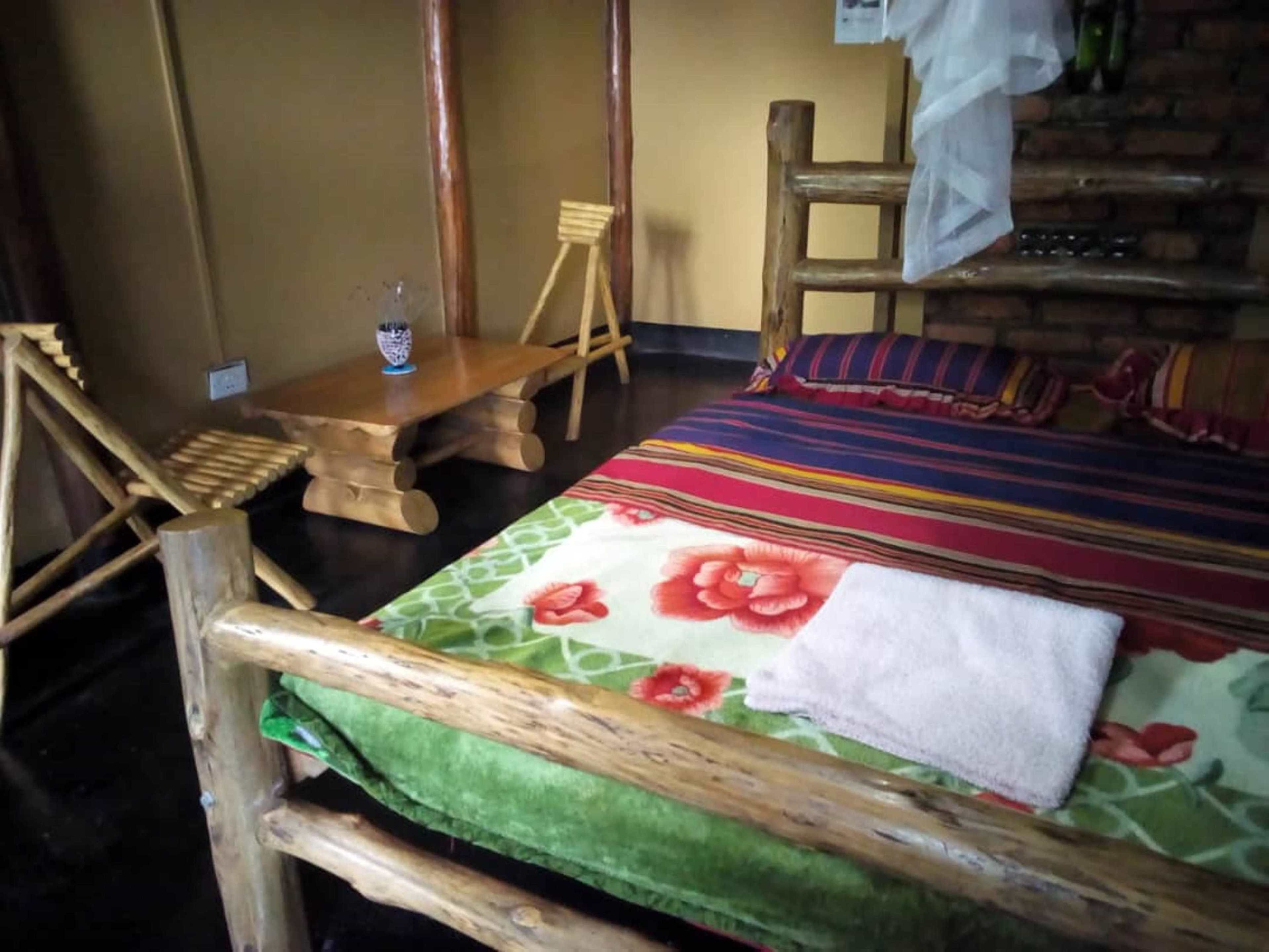 A rustic room with a wooden bed, a small wooden table, and a chair.