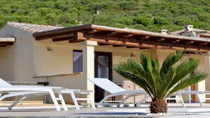 Un bâtiment avec un toit en tuiles, une porte et un petit palmier devant.