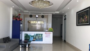 A reception area with a reception desk, a chandelier, a sofa, a coffee table, and a painting. - Padama Hotel (Bai Chay)