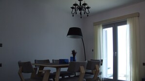 Ein Essbereich mit Tisch und Stühlen, einer Stehlampe und Blick ins Freie durch eine Schiebetür.