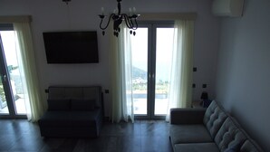 Ein geräumiges Wohnzimmer mit einer großen Couch, einem kleineren Sofa und einem flachbildschirmfernseher an der Wand.
